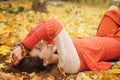 Happy resting girl portrait, lying in autumn maple leaves in park, closed eyes, dressed in fashion sweater