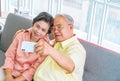 Happy retired couple using mobile phone to take selfie photography picture on a sofa at home