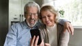Happy retired family couple using mobile phone for video call