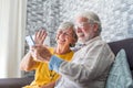 Happy retired family couple using mobile phone for video call together, talking to relations, getting good news, having fun, Royalty Free Stock Photo