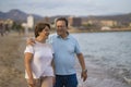 Happy retired mature couple walking on the beach - pensioner woman and her husband taking romantic walk together enjoying sweet Royalty Free Stock Photo