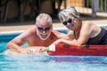 Happy retired senior caucasian couple enjoy together the summer with an active lifestyle at the pool - people with age have fun Royalty Free Stock Photo