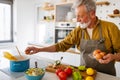 Happy retired senior man cooking in kitchen. Retirement, hobby people concept