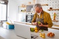 Happy retired senior man cooking in kitchen. Retirement, hobby people concept