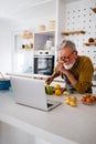 Happy retired senior man cooking in kitchen. Retirement, hobby people concept Royalty Free Stock Photo