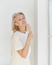 Happy retired woman having fun at home, singing with hairbrush her favourite song and looking in window Royalty Free Stock Photo