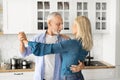 Happy Retirement. Beautiful Senior Couple Dancing In Kitchen Interior