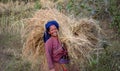 Happy rice field worker, woman carries a big bundle of straw, Nepal