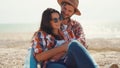 happy romantic couple sits on sea beach, talks, laughs and hugs