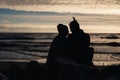 Happy romantic couple sitting on the beach near ocean, relaxing, holding around each other. Royalty Free Stock Photo