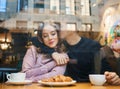 Happy romantic couple sitting over the window in cafe, embracing, kissing and drinking coffee. boyfriend tenderly Royalty Free Stock Photo