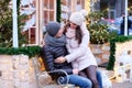 Happy romantic couple wearing warm clothes, enjoying spending time together on a date, hugging while sitting on a bench Royalty Free Stock Photo