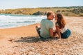 Happy romantic couple woman and man sitting on the beach near the sea and hug each other Royalty Free Stock Photo