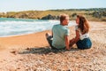 Happy romantic couple woman and man sitting on the beach near the sea and hug each other Royalty Free Stock Photo