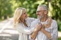 Happy romantic mature couple embracing while walking together in city park Royalty Free Stock Photo