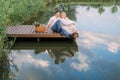 Happy romantic mature couple sitting on a wooden bridge near lake or pond outdoors Royalty Free Stock Photo