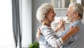 Happy romantic older retired family couple dancing at home.