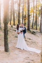 Happy romantic newly married couple holding each other in the autumn pine forest Royalty Free Stock Photo