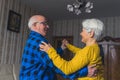 Happy romantic old married couple laughing and dancing in the living room, holding hands, having fun in retirement Royalty Free Stock Photo