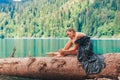 Happy romantic woman sitting by lake splashing water at perfect blue Lake Ritsa. Abkhazia Royalty Free Stock Photo