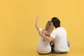 Happy romantic young caucasian couple in white t-shirts hugging, show finger to empty space, sit on floor Royalty Free Stock Photo