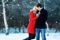 Happy romantic young couple walking in winter park on flying snowflakes snowy