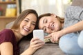 Happy roommates watching on line content in a phone