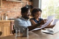 Happy 30s african ethnicity biracial family couple involved in paperwork.