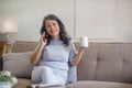 A happy 60s Asian woman enjoys her coffee and talking on the phone Royalty Free Stock Photo