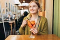 Happy 30s girl sitting on the cafe terrace on the city street. Woman hands toasting with aperol spritz cocktail. Concept Royalty Free Stock Photo