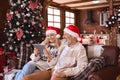 Happy 50s older couple using digital tablet in living room on Christmas. Royalty Free Stock Photo