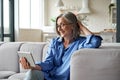 Happy 60s mature woman calling or watching video digital tablet at home. Royalty Free Stock Photo