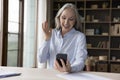 Happy 60s woman waving hand hello at smartphone screen Royalty Free Stock Photo