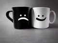 Happy and sad smiley icon on mugs in vintage background. Stock photo. Royalty Free Stock Photo