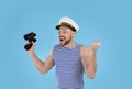 Happy sailor with binoculars on light blue background