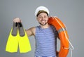 Happy sailor with ring buoy and swim fins on grey background