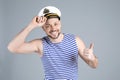 Happy sailor wearing cap on grey background