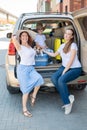 Happy same-sex family going on a car trip around the country. Lesbian couple with son and dog are loading luggage in the Royalty Free Stock Photo