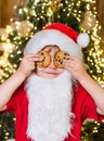 Happy Santa Claus - cute boy child eating a cookie and drinking glass of milk at home Christmas interior. Little Santa