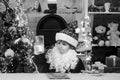 Happy Santa Claus helper with glass of milk and cookie. Little Santa picking cookie and glass of milk at home.