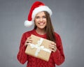 Happy Santa girl holding Christmas gift, wearing red hat. Royalty Free Stock Photo