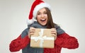 Happy Santa girl holding Christmas gift, wearing red hat. Royalty Free Stock Photo