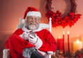 Happy santa sitting on chair and using mobile phone Royalty Free Stock Photo