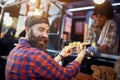 Happy, satisfied caucasian beardy male customer taking  sandwiches from a polite employee in fast food service, looking at camera Royalty Free Stock Photo