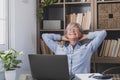 Happy satisfied caucasian mature woman rest at home office sit with laptop hold hands behind head, dreamy old senior relax