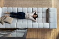 Happy satisfied lazy Asian woman relaxing on big comfortable couch