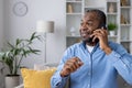 Happy and satisfied man talking on the phone sitting at home on the sofa in the living room, mature senior African Royalty Free Stock Photo