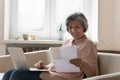 Happy satisfied senior woman reviewing financial paper at home