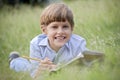 Happy school boy doing homework and smiling, lying on grass Royalty Free Stock Photo