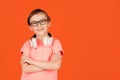 Happy school boy with headphones against orange background
